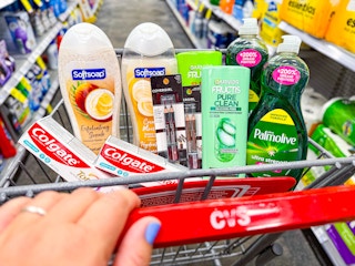 person pushing a cart with colgate toothpaste, softsoap body wash, covergirl eyeliner, garnier shampoo, and palmolive dish soap