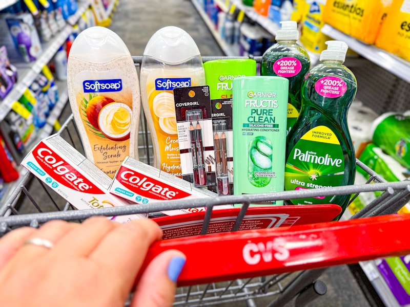 person pushing a cart with colgate toothpaste, softsoap body wash, covergirl eyeliner, garnier shampoo, and palmolive dish soap