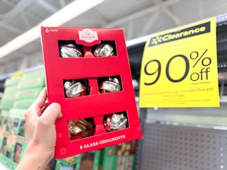 hand holding a pack of glass ornaments in walmart aisle