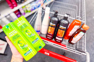 person holding garnier shampoo over a cart with nexxus, tresemme, and garnier whole blends shampoo in it