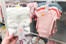 hand holding carter's baby bodysuits in front of bodysuits