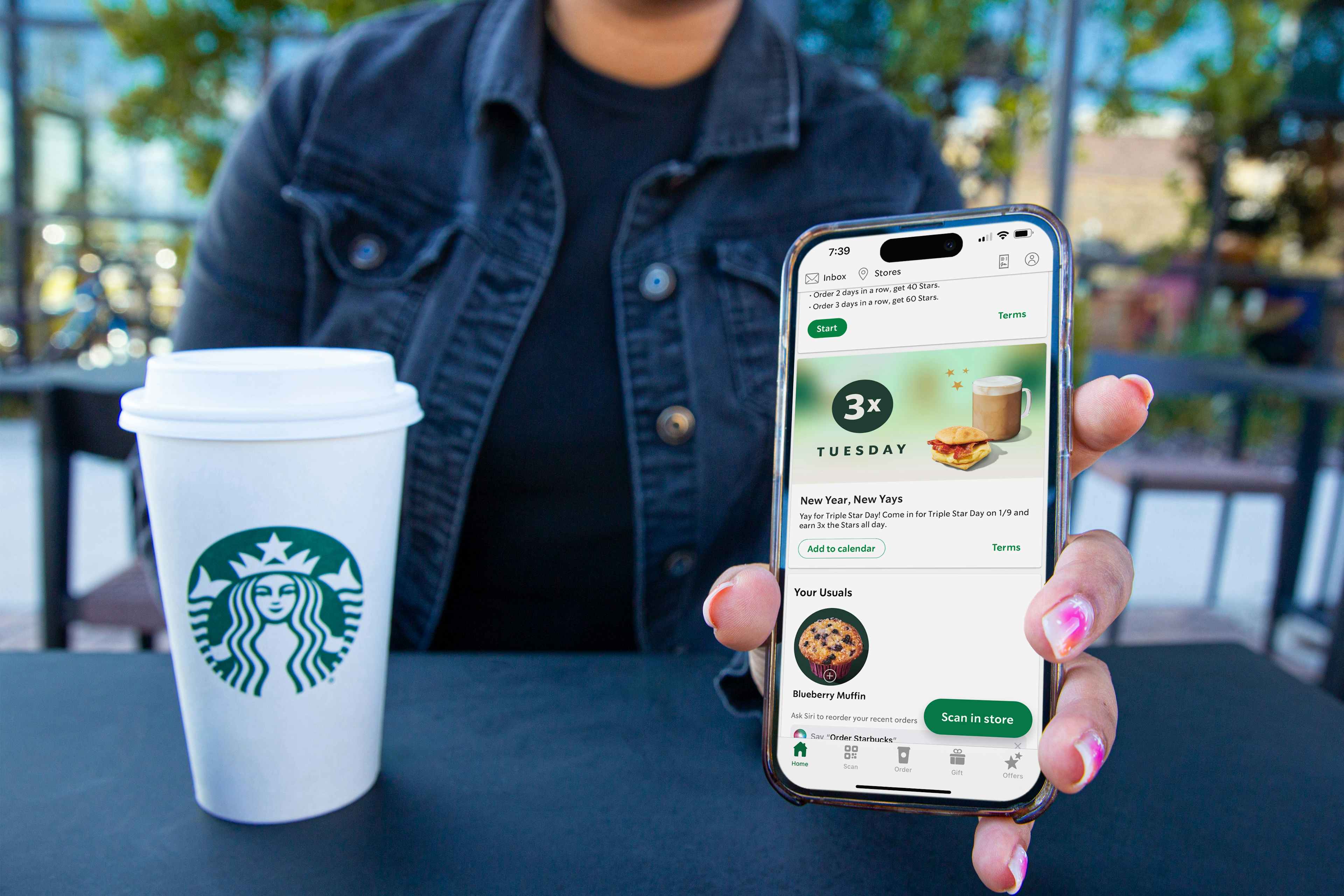 someone holding a phone showing a starbucks email about their triple star day on january 9th