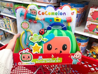 hand holding cocomelon toy in Target shopping cart