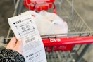 a hand holding a cvs extra bucks rewards receipt next to a cvs cart 