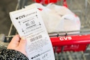 a hand holding a cvs extra bucks rewards receipt next to a cvs cart 