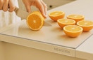 a person cutting oranges on an acrylic cutting board