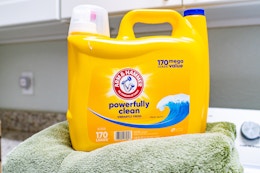 a yellow jug of detergent on a towel on a washing machine