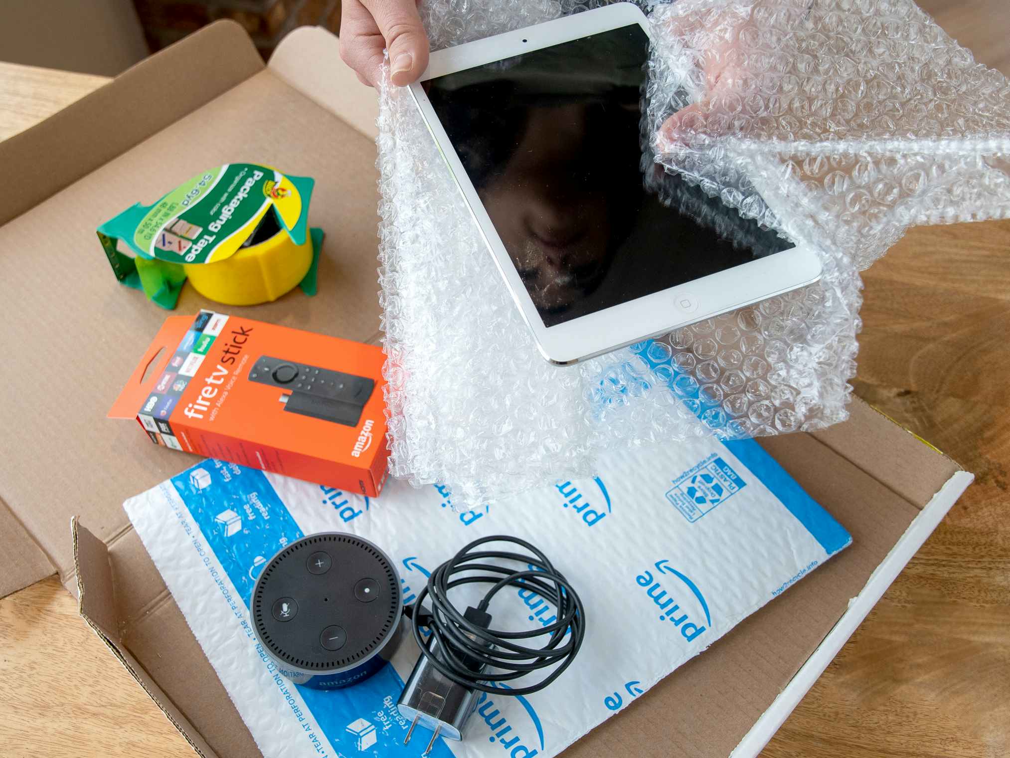 An iPad, Amazon Fire stick, and Amazon Echo dot being boxed up to ship