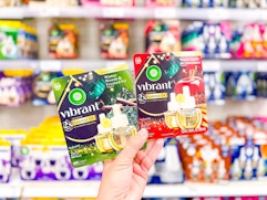 hand holding 2 air wick essentials oils refills in front of target shelves