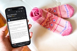 someone holding a phone showing an email telling them to keep their product and that they will still get a refund