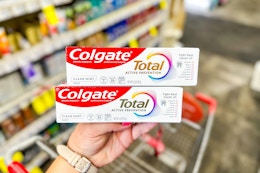 hand holding two tubes of colgate total toothpaste