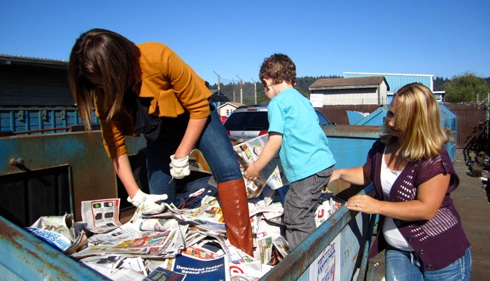 people in dumpster grabbing papers