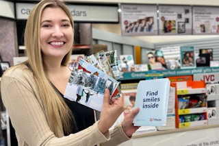 person holding photos at walgreens photo counter 