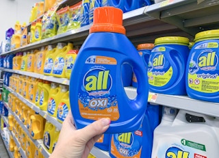 bottle of all oxi liquid laundry detergent held up in front of other laundry detergents in walmart store aisle