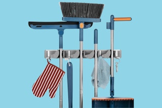 An aluminum storage rack holds an oven mitt, a squeegee, a broom, and several other tools.