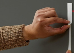 a person putting Command strips on a wall