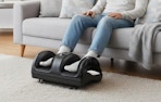 a person sitting on a couch with a foot massager