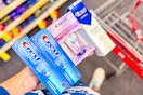 person holding 4 crest toothpastes by a cvs cart