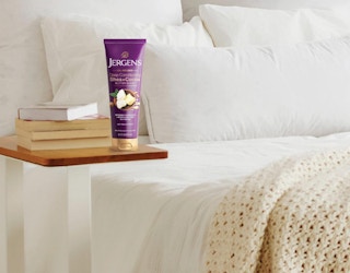 a purple tube of lotion on a small table next to a bed