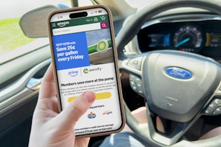 someone on the phone in their car looking at the amazon prime gas deal