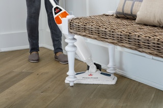 stock photo of woman using bissell powerfresh steam mop in an entryway under a bench