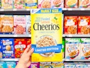 hand holding a box of frosted lemon cheerios in walmart cereal aisle