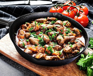 a cast iron skillet on a serving board with food inside