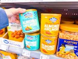 hand grabbing a container of Roasted Sea Salt Almonds and More of the shelf