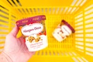 hand holding haagen-dazs ice cream over a yellow shopping basket