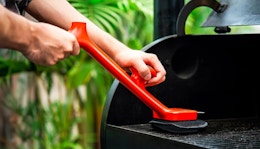 a person cleaning a grill with a steam brush 