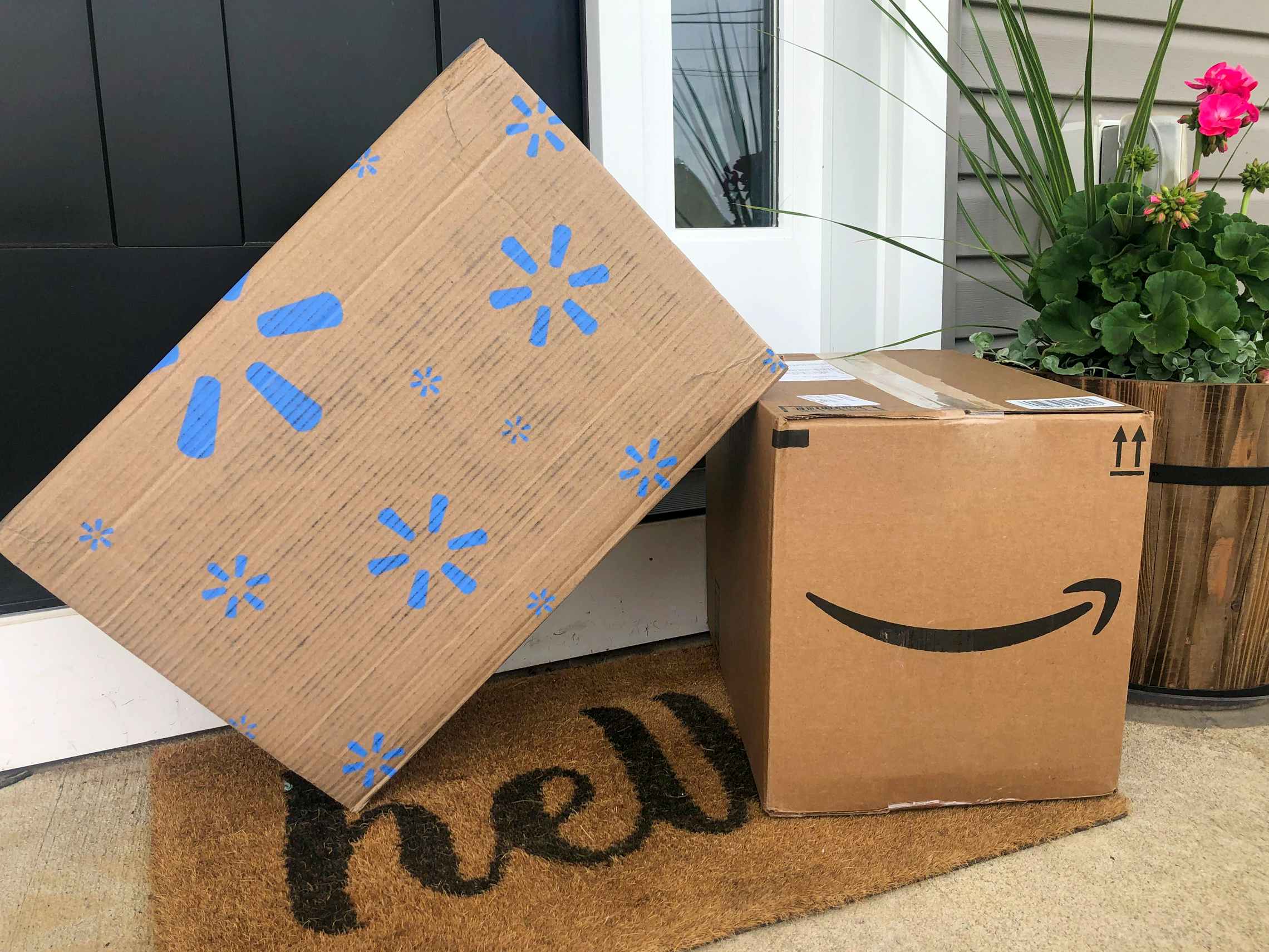 An Amazon and Walmart delivery box sitting on a front doorstep.
