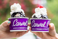 Two people holding up cups of Carvel ice cream