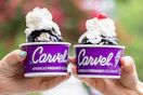 Two people holding up cups of Carvel ice cream