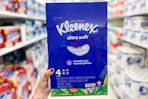hand holding a 4-pack of kleenex ultra soft tissues in a target aisle