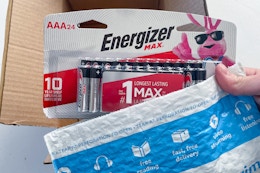 a hand holding a battery above a box of batteries