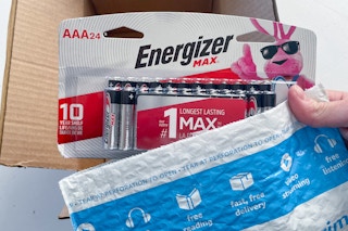 a hand holding a battery above a box of batteries