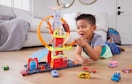 a kid on the floor playing with a Hot Wheels playset