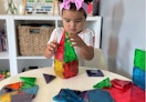 a little kid playing with magnetic tiles