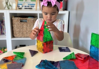 a little kid playing with magnetic tiles