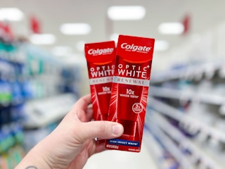 two red boxes of toothpaste in a hand