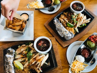 A person taking a fry from a plate sitting next to other plates of food on a table at Chili's.