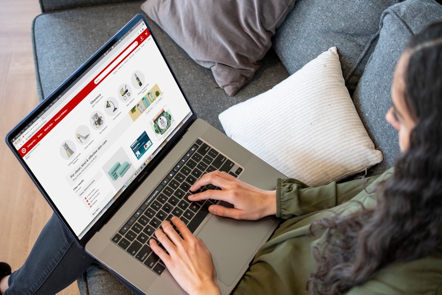 A Woman sitting on a sofa with a laptop on her lap displaying the target.com clearance page