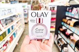 person holding olay super serum in an aisle