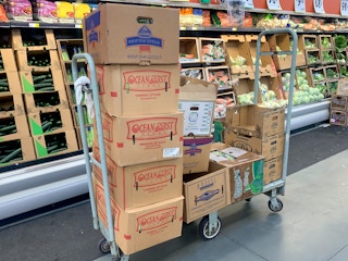 Cardboard produce boxes on a cart inside Winco.