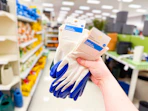 hand holding 2 sets of gardening gloves in a target aisle