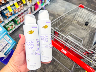 person holding 2 dove whole body deodorants over a cvs cart