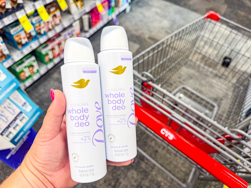 person holding 2 dove whole body deodorants over a cvs cart