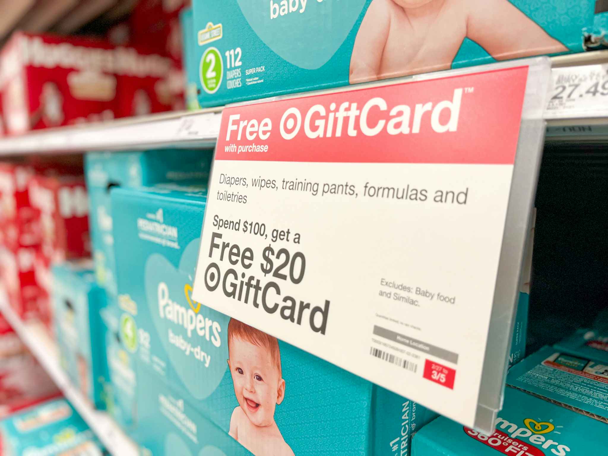 A shelf filled with pampers baby diapers with a sign that says Free Target Gift Card with $100 purchases of diapers, wipes, training pant...