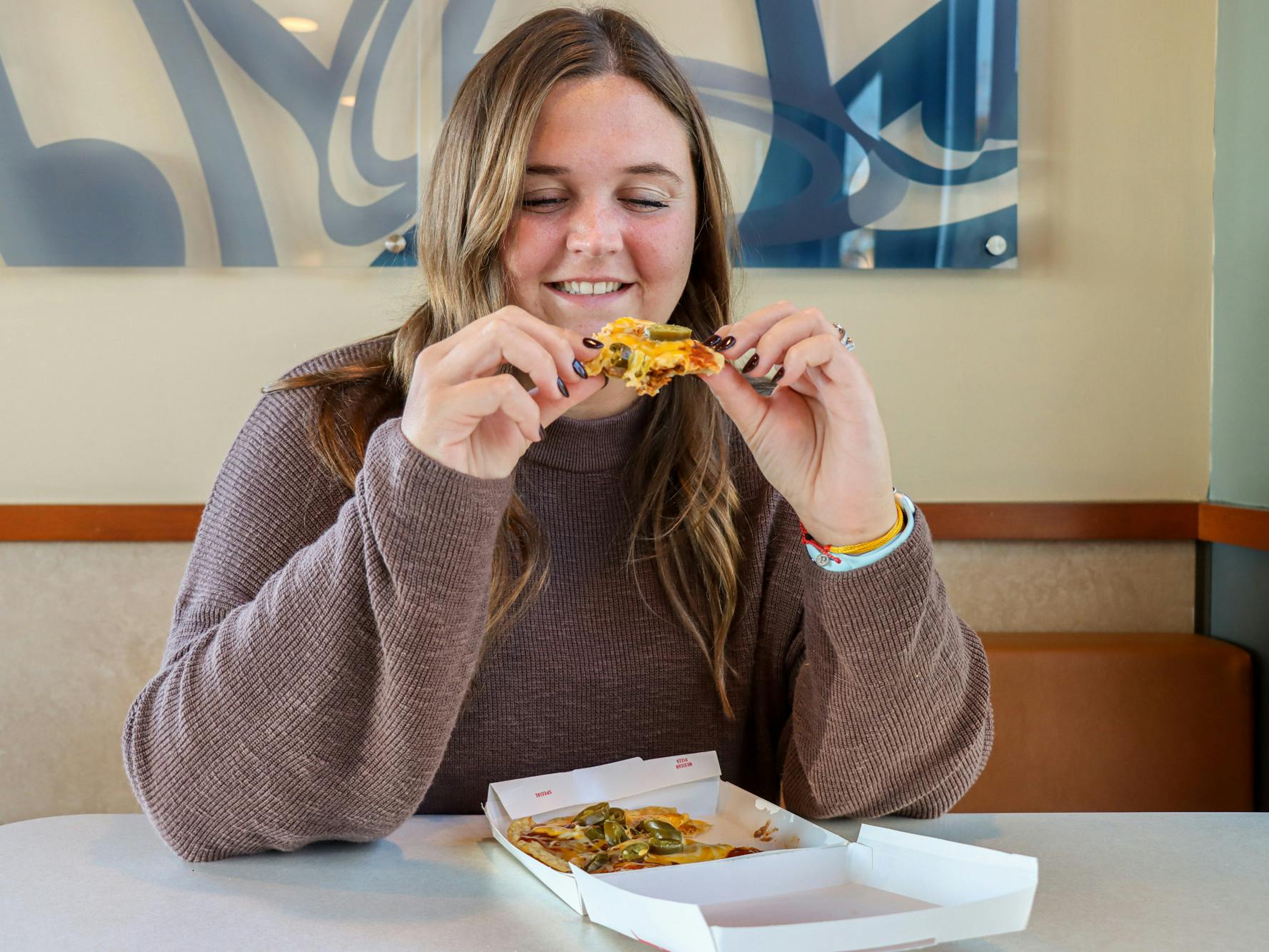 a person sitting in taco bell with a mexican pizza