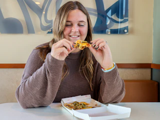 a person sitting in taco bell with a mexican pizza